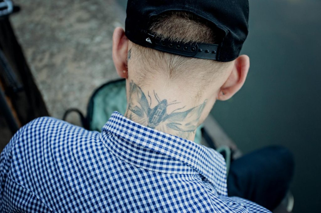 man with insect tattoo on neck
